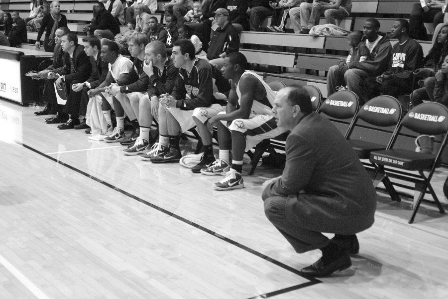 Head Coach Bobby Champagne and the men’s basketball team watch the game from their courtside bench area earlier this season.