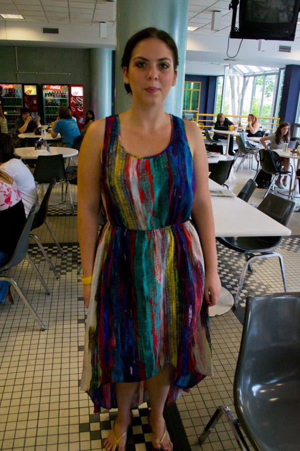 A student in the GUC wears a colorful, bright and summer appropriate dress that features gathering at the waist and a playful dress length. 
