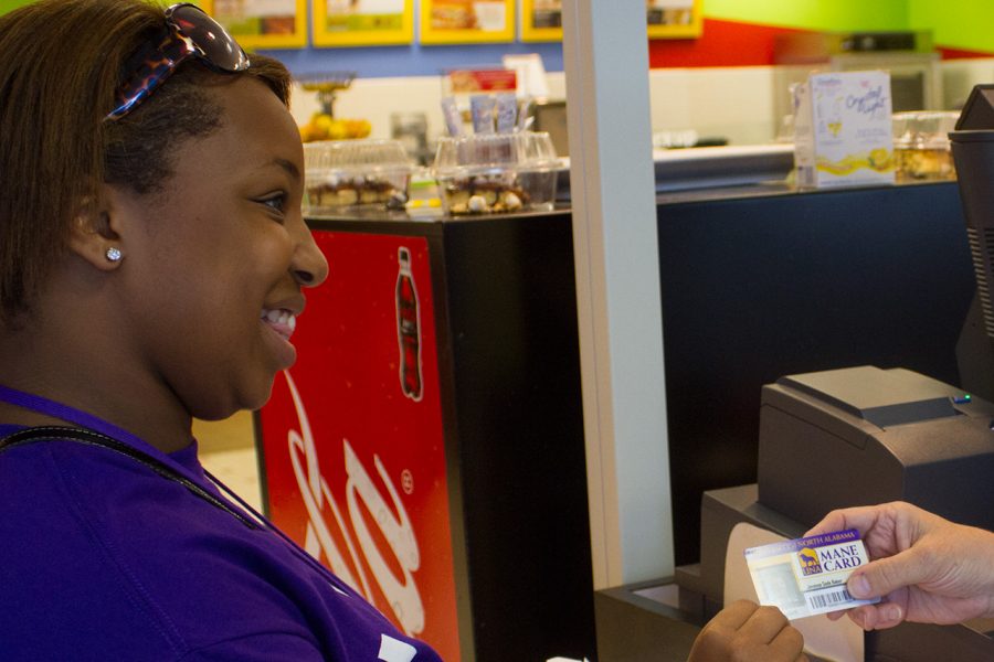 UNA student Javonne Baker uses her Mane Card to make a purchase at the GUC. While students can add money to their Mane Cards, some universities offer student ID cards that function as true debit cards.
