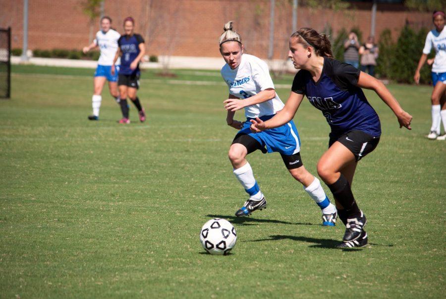 UNA’s Emily Black carries the ball down field with UAH’s Emily Hancock hot on her heels in the Sept. 9 game.

