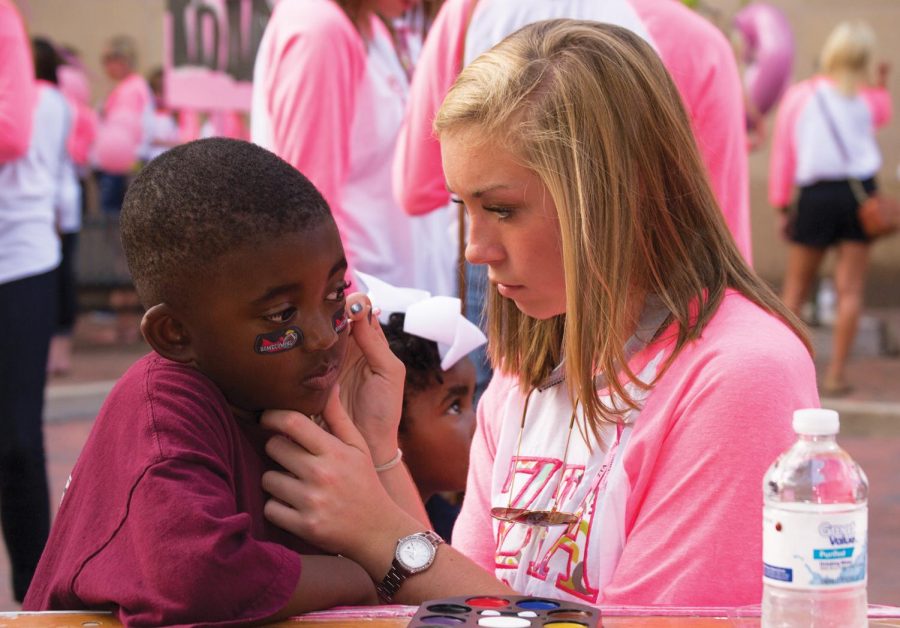 Emily Manush paints Miles Colley’s face during Zeta Tau Alpha’s Pink Party, held in Florence during First Fridays on Oct. 5. Pink Party was the last in a series of events that make up ZTA’s Pink Week, a fundraiser for Breast Cancer Awareness.