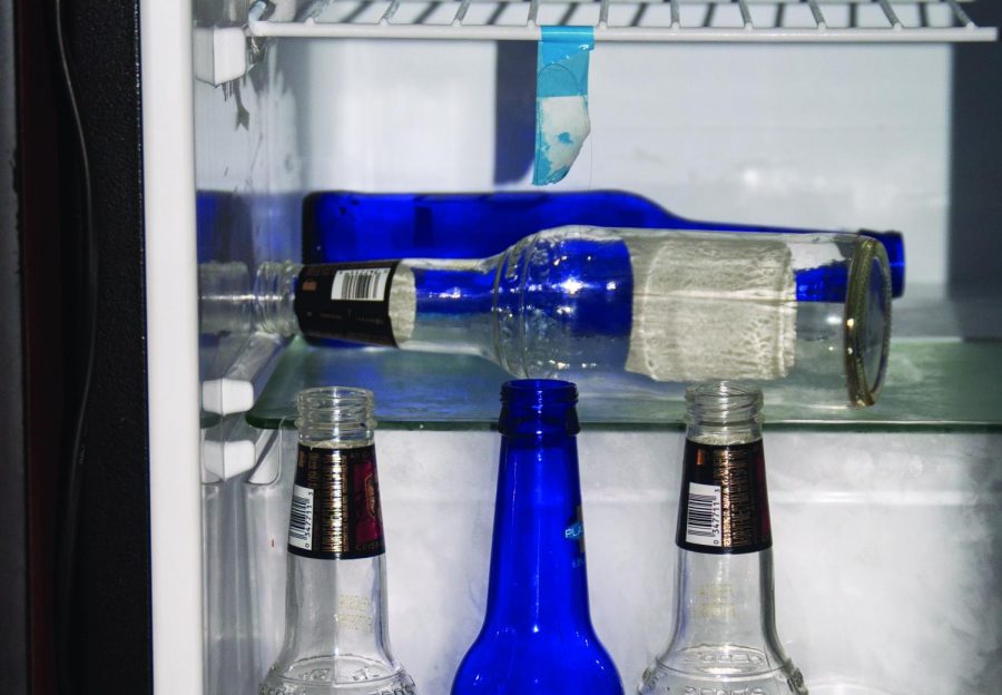 Empty liquor bottles line the interior of a dorm-sized refrigerator. The university’s 2013 Clery Report indicates an increase of 31 case referrals for on campus liquor law violations from 2011 to 2012.