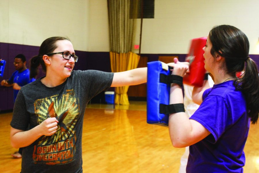 Student Melissa Bonnefield punches the training pad held by Rebecca Hardiman during class.