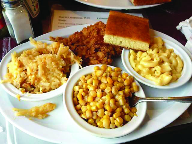 A breast of fried chicken steams alongside bowls of corn, macaroni and cheese, potato casserole and a slice of fresh corn bread at Garden Gate Cafe.