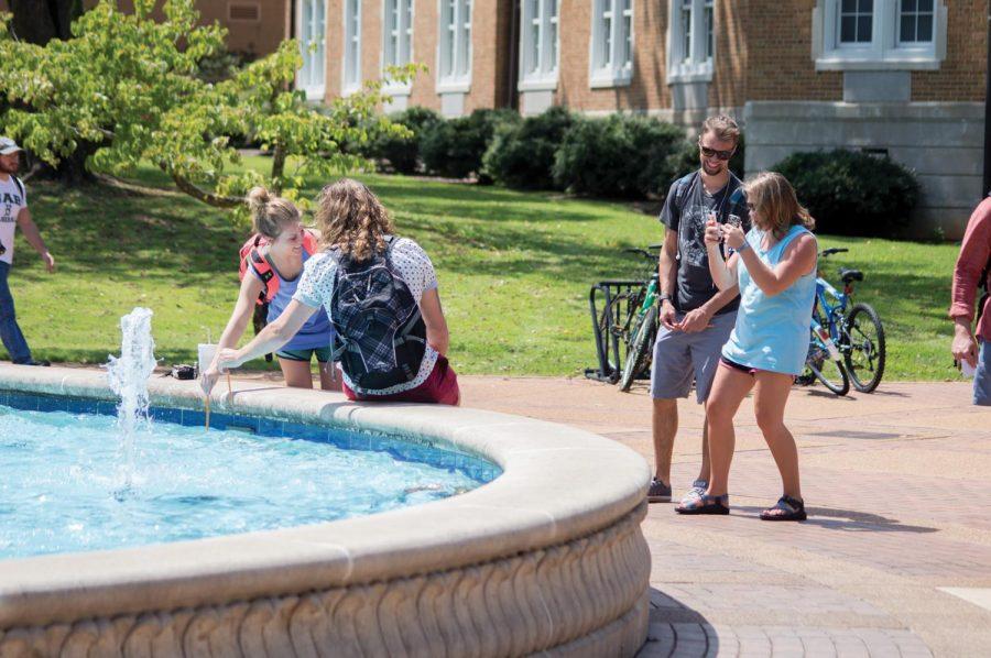 Two+students+dip+their+pencils+in+the+fountain+on+the+first+day+of+school+as+another+student+takes+their+photo.+SGA+members+said+they+wanted+to+bring+back+the+dip+because+it+has+been+a+campus+tradition+in+the+past.