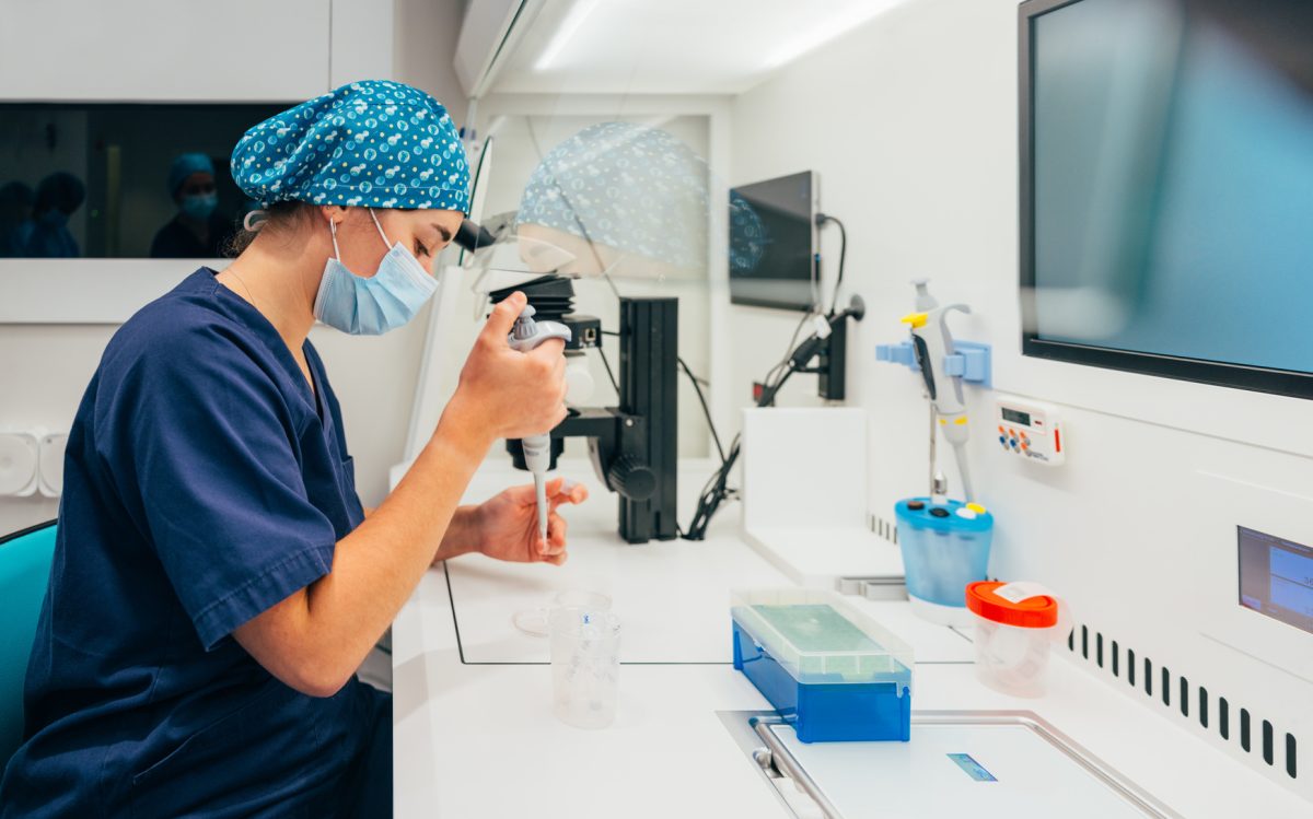 Side view of female scientist in medical uniform conducting in vitro fertilization in petri dish while working in modern clinic. 