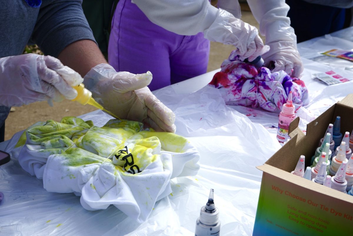 Participants are seen dyeing their clothes at Tie (Dye) versity event near the memorial amphitheater. 